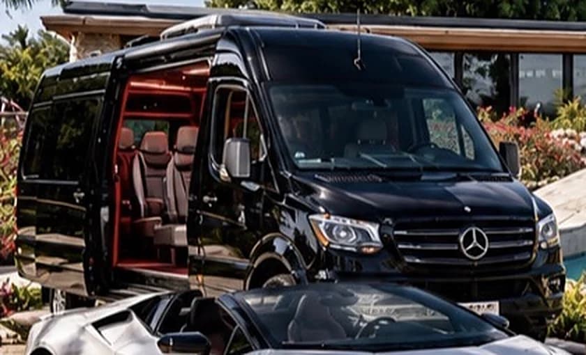 Black Mercedes-Benz Sprinter executive van with its side door open showing red and cream seats