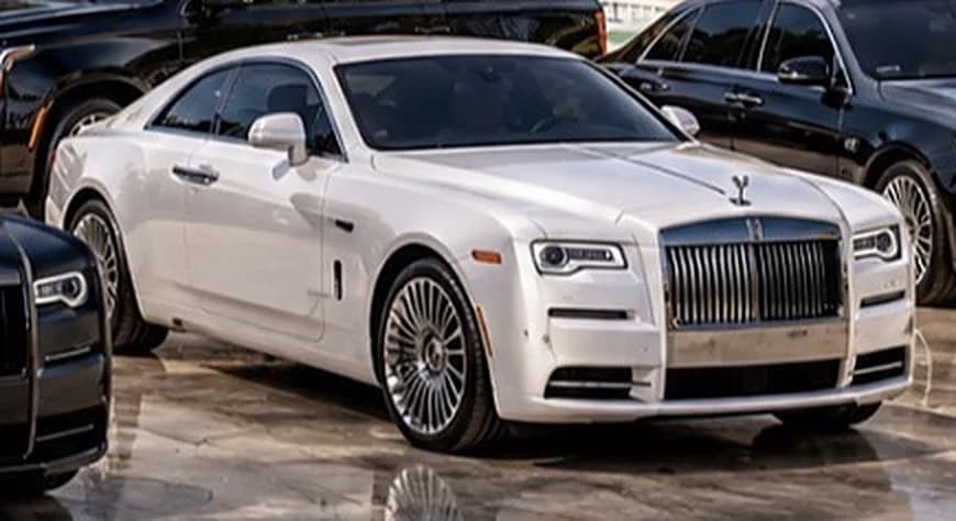 White Rolls-Royce fastback coupé with polished wheels on a stone forecourt