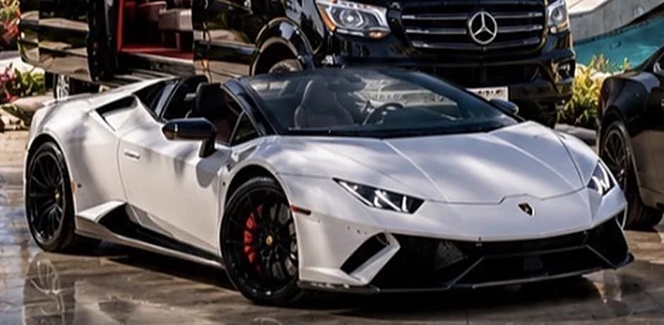 White Lamborghini Huracán Spyder with its roof down on a polished stone forecourt